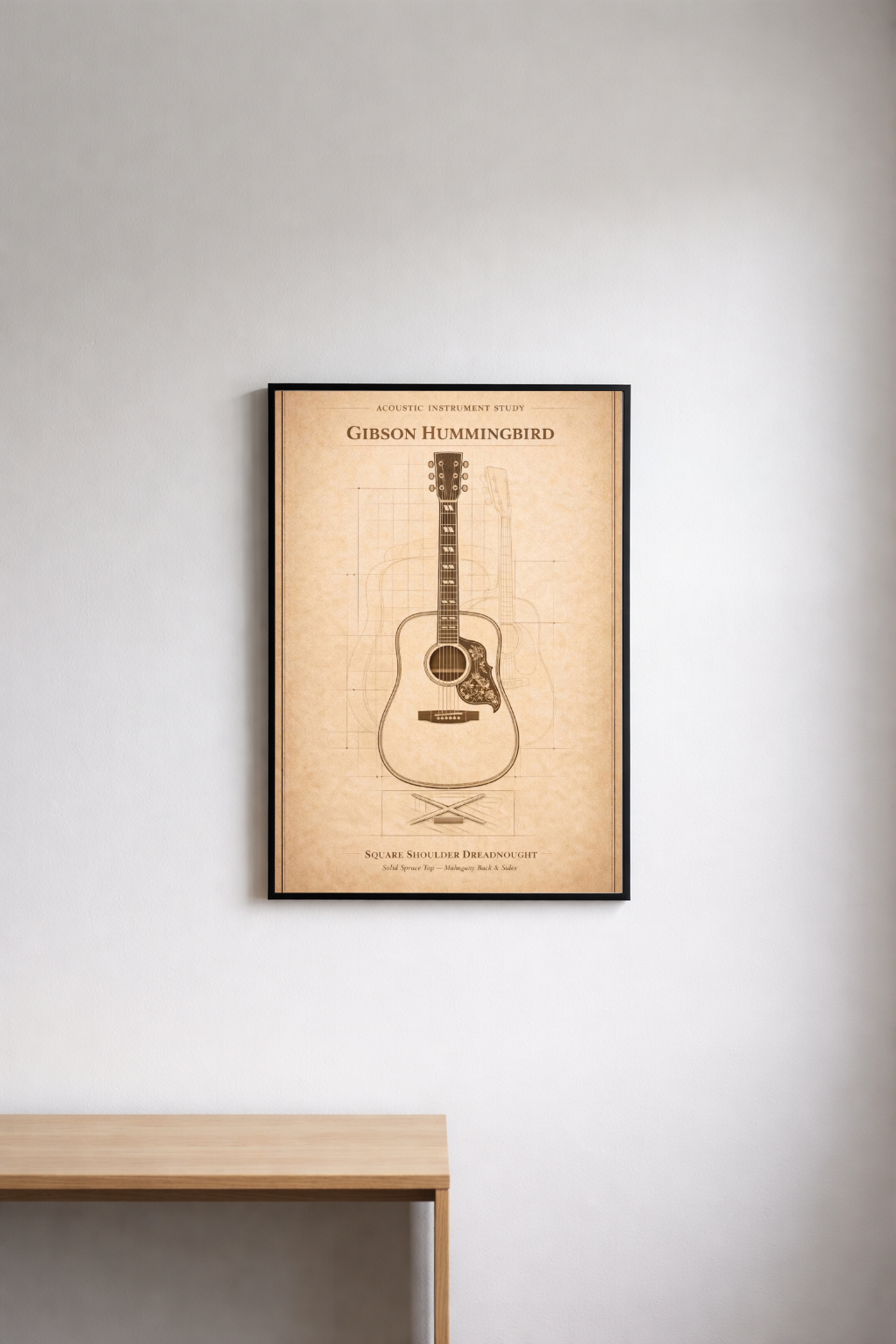 Framed poster of a Gibson Hummingbird guitar on a wall above a wooden table.