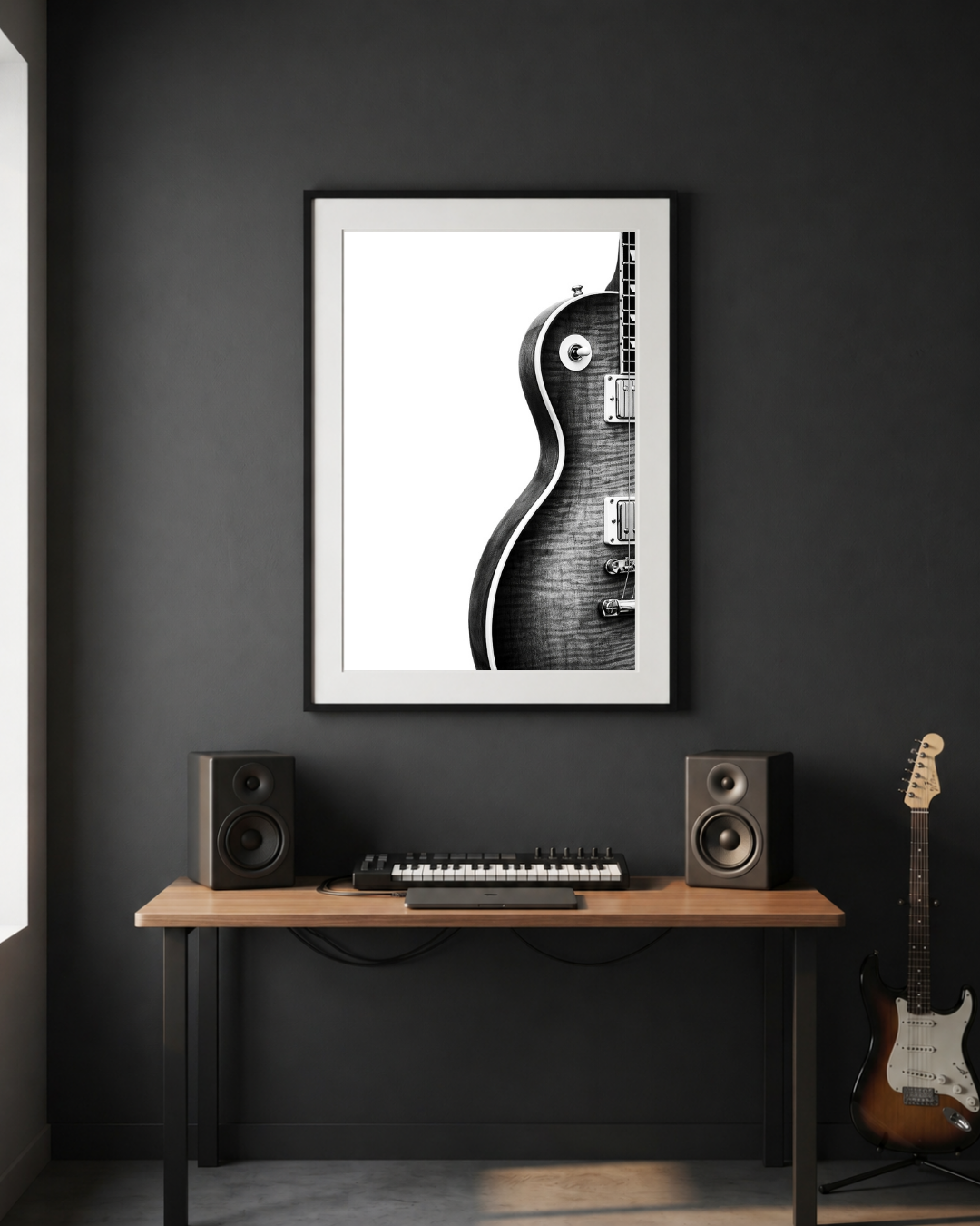Framed guitar art print on a dark wall above a desk with speakers and a guitar.