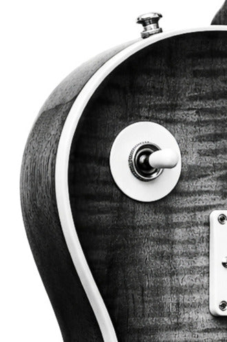 Close-up of a les paul guitar's control knob and wood grain texture.