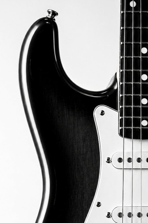 Close-up of a black Stratocaster electric guitar on a white background