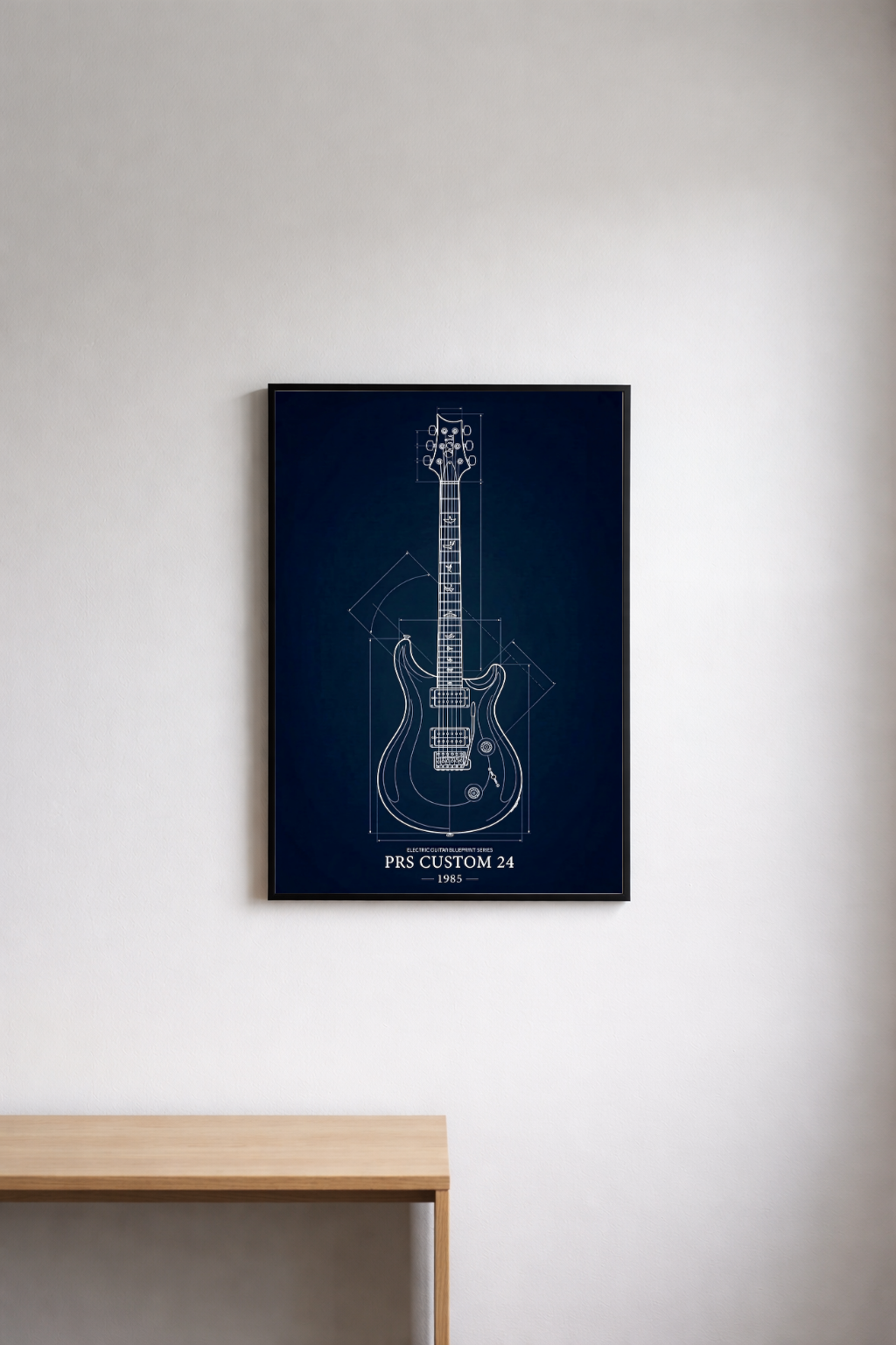 Framed guitar blueprint on a white wall above a wooden table