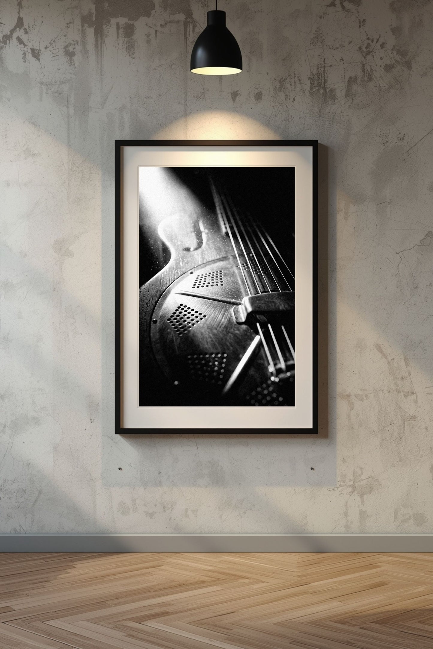 Framed black and white artwork of a resonator guitar on a textured wall.