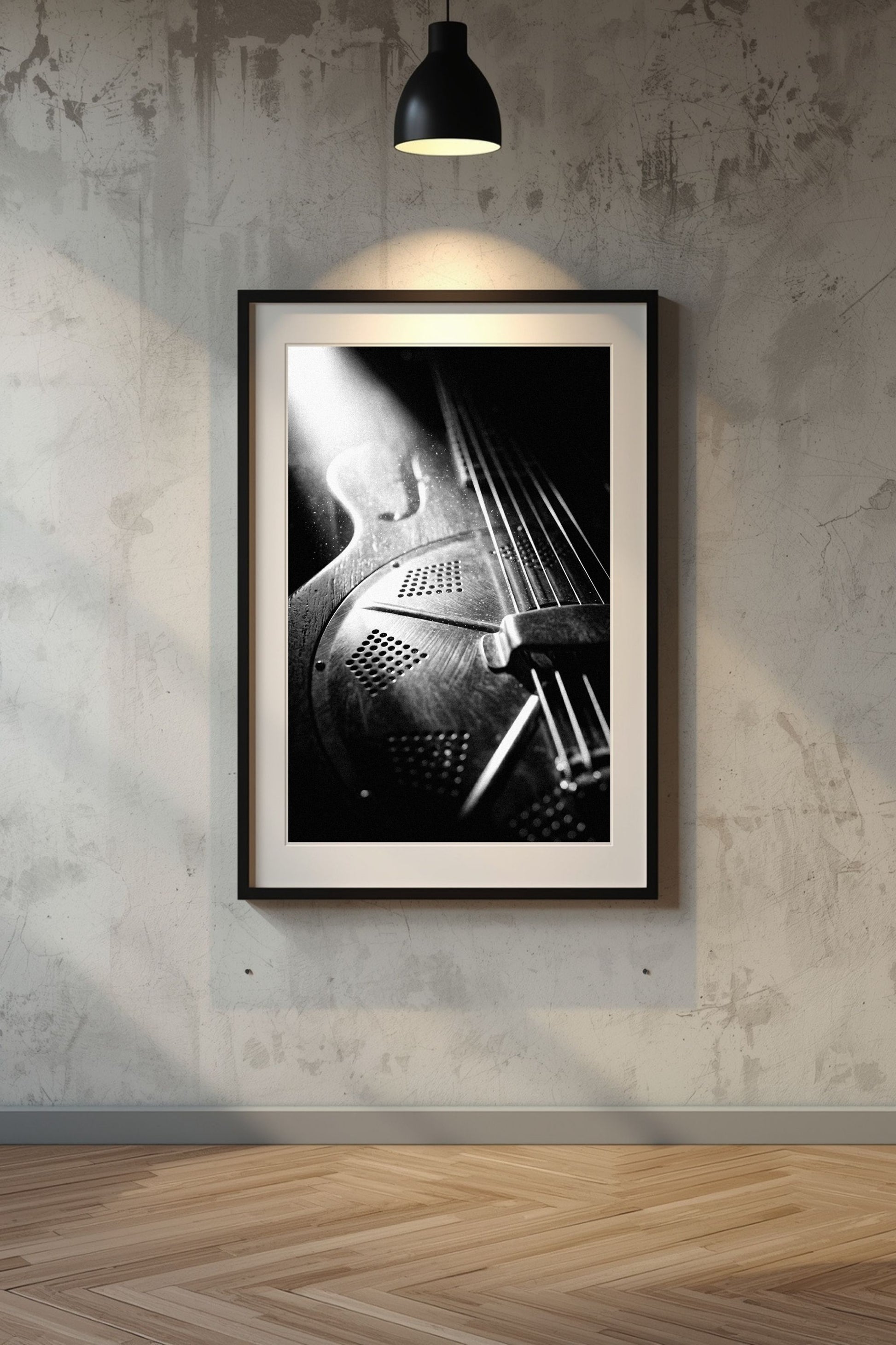 Framed black and white artwork of a resonator guitar on a textured wall.