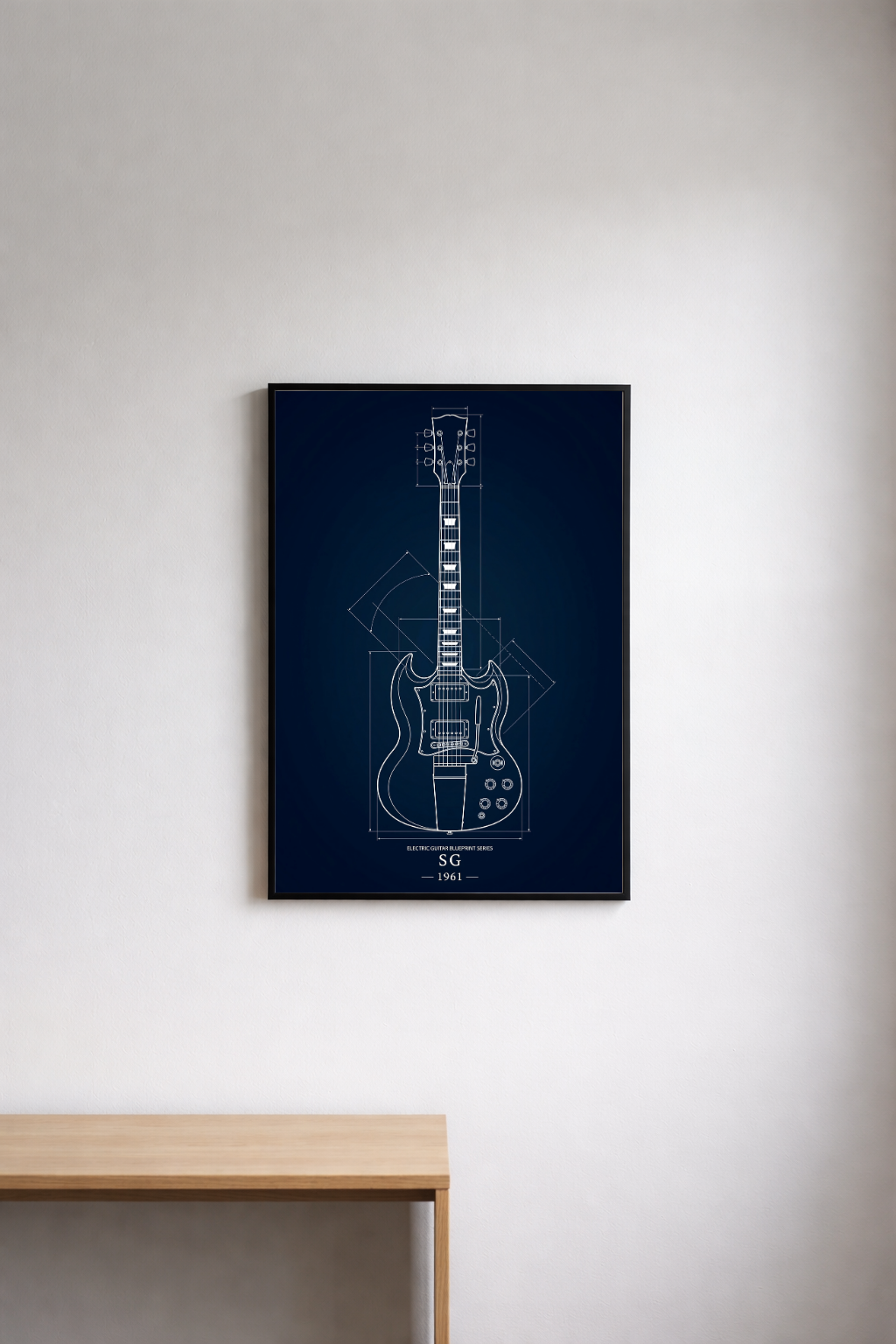 Framed guitar blueprint on a white wall above a wooden table