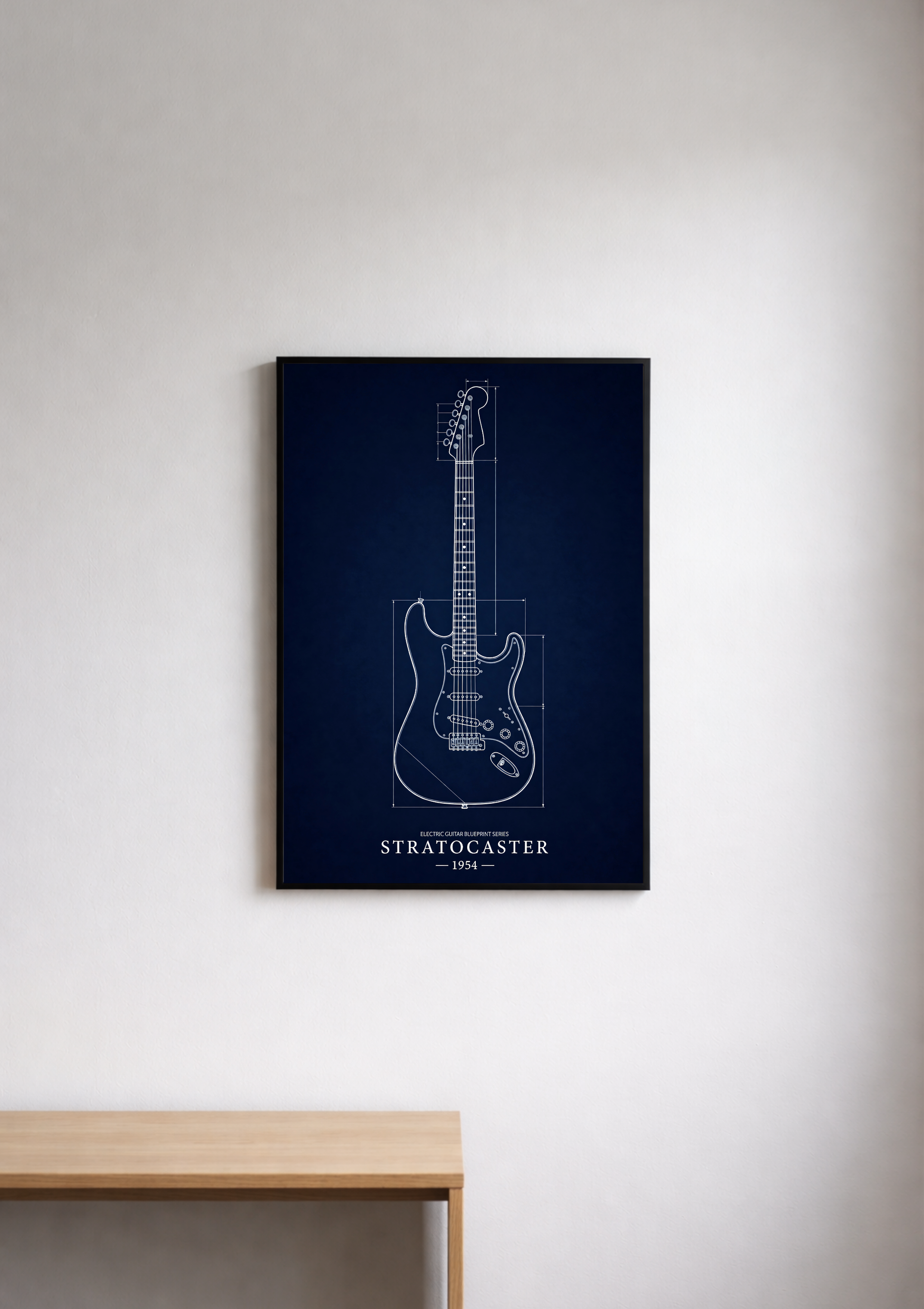 Framed guitar blueprint on a wall above a wooden desk