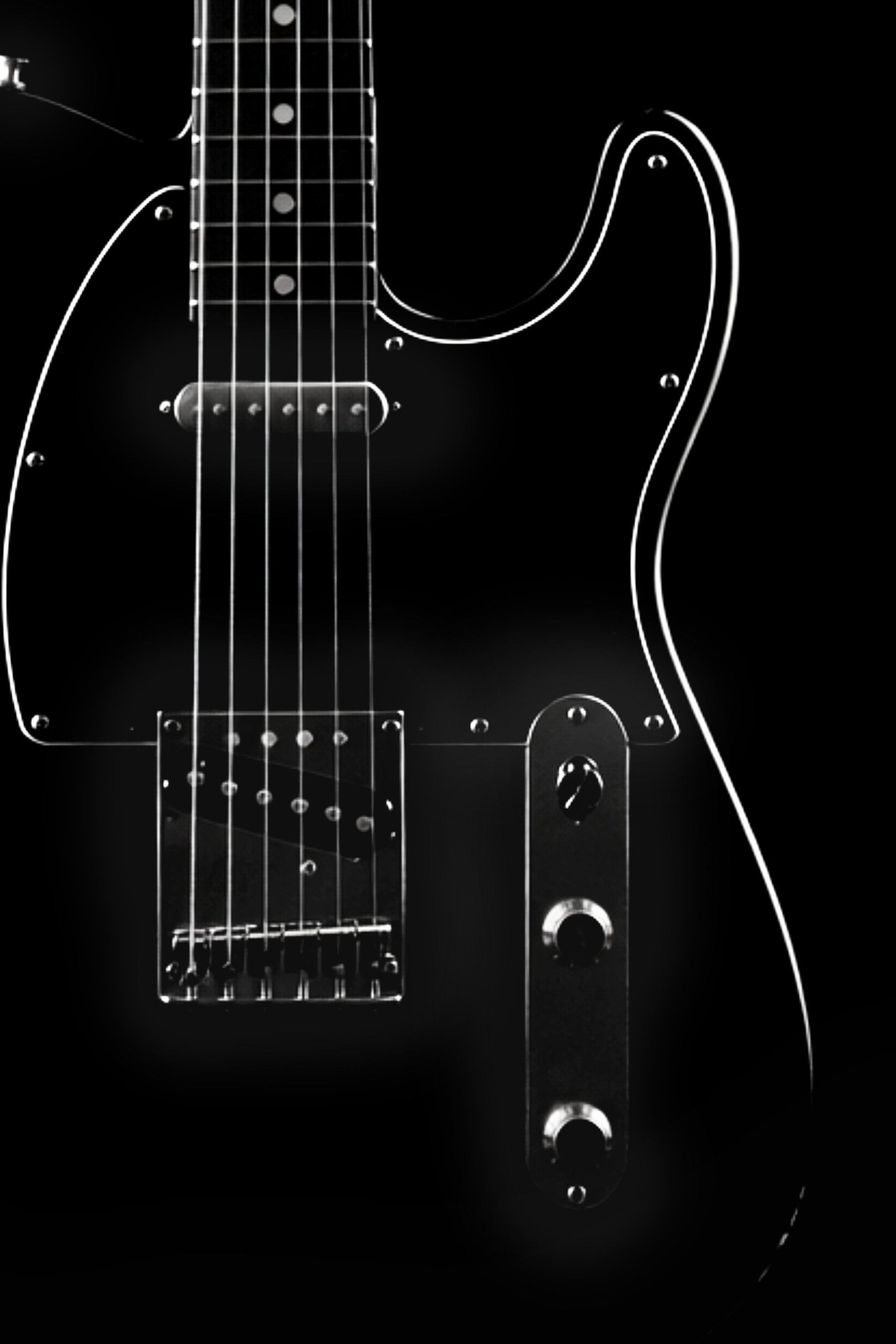 Close-up of a black electric guitar on a black background