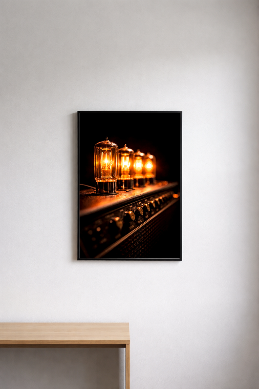Framed photograph of vintage electronic tube amp bulbs on a white wall above a wooden surface.